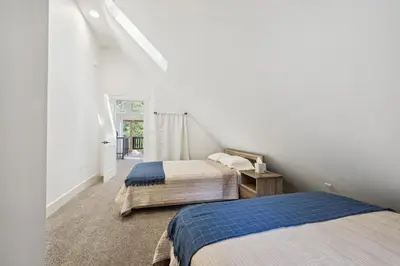 two beds in a room with white walls at Spacious Pine Mountain Lake Cabin Rental with Decks in Groveland