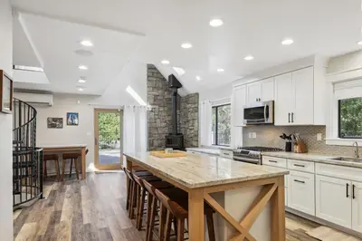 a kitchen with white cabinets and a large island with bar stools at Spacious Pine Mountain Lake Cabin Rental with Decks in Groveland