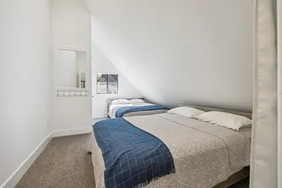 two beds in a bedroom with white walls at Spacious Pine Mountain Lake Cabin Rental with Decks in Groveland