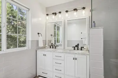 a white bathroom with a sink and a mirror at Spacious Pine Mountain Lake Cabin Rental with Decks in Groveland