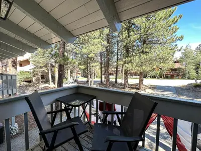 two chairs and a table on a porch with trees at Lakeview Lodge #2 condo in Mammoth Lakes
