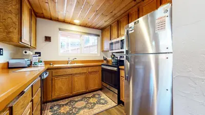 a kitchen with a stainless steel refrigerator and wooden cabinets at Courchevel #5 condo in Mammoth Lakes