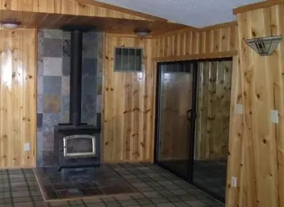 a wood paneled room with a wood burning stove at Tillie Creek Retreat: a Creekside Oasis in Wofford Heights