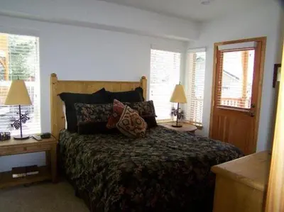 a bedroom with a bed with two tables and two windows at Rr-hideaway_down_canyon110 in June Lake