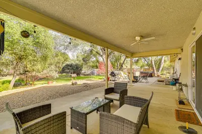 a patio with chairs and a table and a ceiling fan at Private Lake, Hot Tub and EV Charger Mariposa Home! in Mariposa