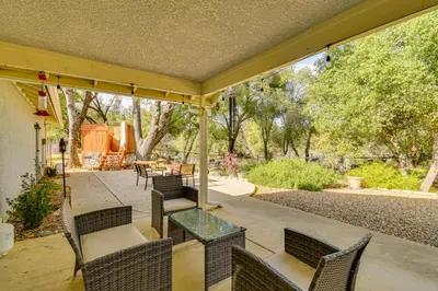 a patio with a glass table and chairs and trees at Private Lake, Hot Tub and EV Charger Mariposa Home! in Mariposa