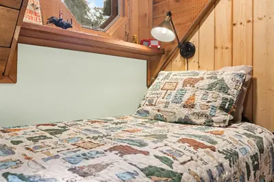 a bedroom with a bed with a quilt and a window at The Knotty Cabin in Kings Canyon National Park in Wilsonia