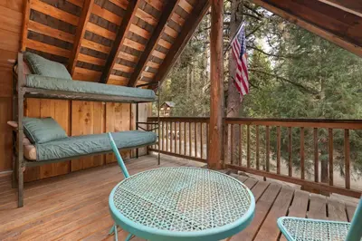 a porch with a table and chairs on a deck at The Knotty Cabin in Kings Canyon National Park in Wilsonia