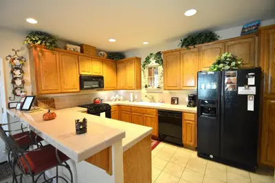 a kitchen with wooden cabinets and a black refrigerator at Forward-Lake Area in Bass Lake