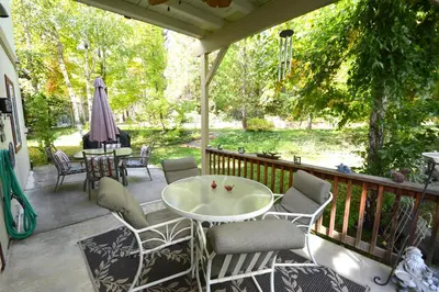 a porch with a table and chairs and an umbrella at Forward-Lake Area in Bass Lake