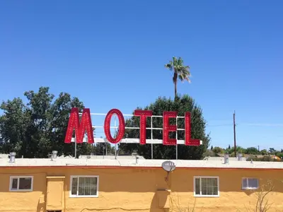 a sign on top of a building with a palm tree at Valley Motel in Atwater