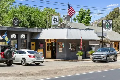 a city street with cars parked in front of a gas station at The Belle Sequoia Motel RM9 in Three Rivers