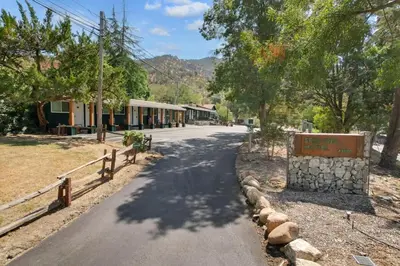 a road in a town with a building and trees at The Atwell Sequoia Motel RM 8 in Three Rivers