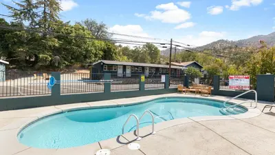 a small swimming pool with a fence and a building at The Whitney- Sequoia Motel RM7 in Three Rivers