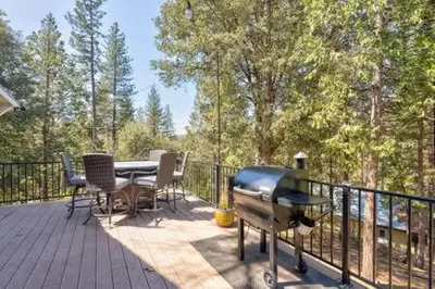 a deck with a table and chairs and a grill at Cedar Ridge Hot Tub BBQ Sleeps 8 in Oakhurst