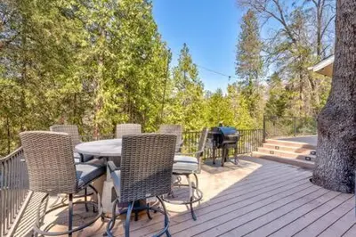 a table and chairs on a deck with a tree at Cedar Ridge Hot Tub BBQ Sleeps 8 in Oakhurst