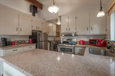 a kitchen with white cabinets and a granite counter top at Cozy Pet-Friendly Cabin w Fenced-In Yard Close to Slopes Beach Town in Carnelian Bay