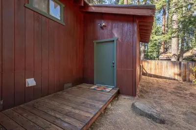 a red building with a green door and a wooden porch at Cozy Pet-Friendly Cabin w Fenced-In Yard Close to Slopes Beach Town in Carnelian Bay