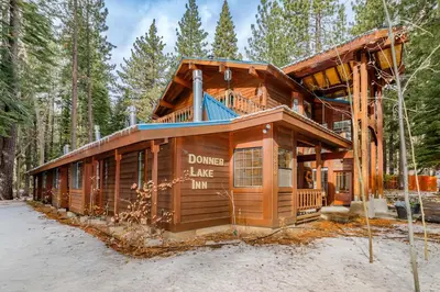 a log home in the woods with a wrap around porch at Donner Lake Inn in Truckee