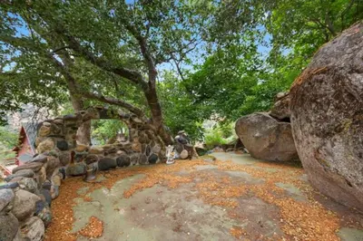 a stone wall with a tree and some rocks at SEQUOIA LOOKOUT LODGE in Three Rivers