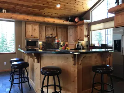 a kitchen with wooden cabinets and bar stools at Large Family Home in Quiet Wooded Setting Close to Everything in Mevers