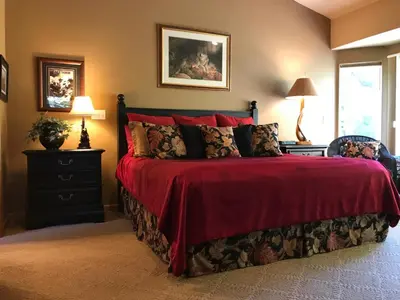 a bedroom with a bed with a red bedspread at Large Family Home in Quiet Wooded Setting Close to Everything in Mevers