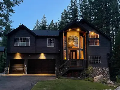 a black house with a garage at night at Large Family Home in Quiet Wooded Setting Close to Everything in Mevers