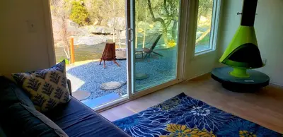 a living room with a couch and a sliding glass door at Retro House on the River ! in Three Rivers