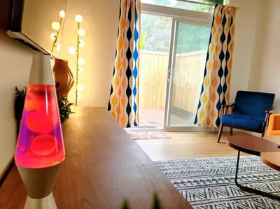 a living room with a table and a blue chair at Retro House on the River ! in Three Rivers