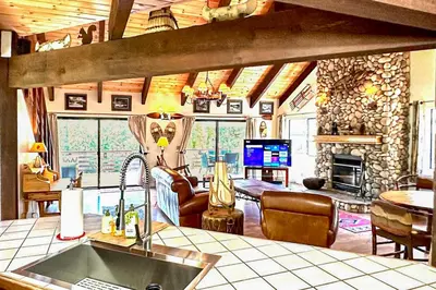 a kitchen and living room with a stone fireplace at Wishing Well Cabin in Bass Lake