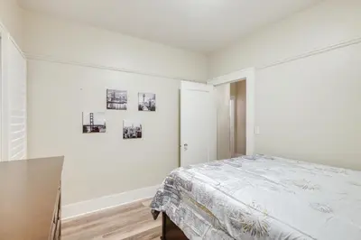a white bedroom with a bed and pictures on the wall at Sunny Turlock Cottage Walk to Downtown! in Turlock