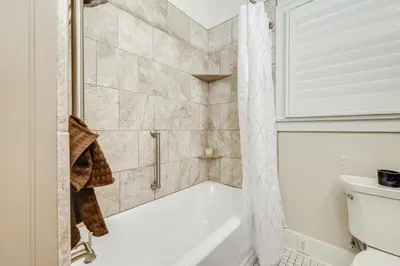 a bathroom with a shower with a tub and a toilet at Sunny Turlock Cottage Walk to Downtown! in Turlock
