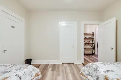 two beds in a bedroom with white walls and wooden floors at Sunny Turlock Cottage Walk to Downtown! in Turlock