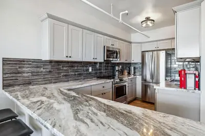 a kitchen with white cabinets and a marble counter top at Mtn-View Apt with Deck in Historic Virginia City in Virginia City