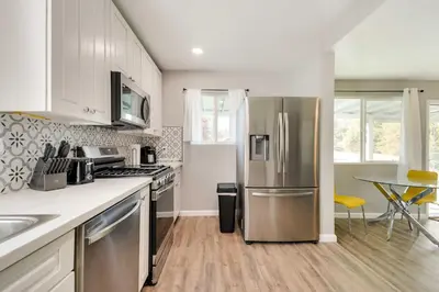 a kitchen with a stainless steel refrigerator and a table at Waterfront Mariposa Hideaway Hot Tub and Mtn Views! in Mariposa