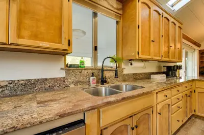 a kitchen with wooden cabinets and a sink at Waterfront Mariposa Vacation Rental with Hot Tub in Mariposa