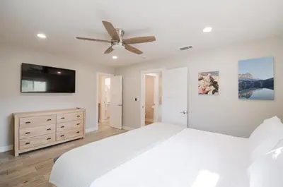 a white bedroom with a bed and a ceiling fan at Dennison House in Three Rivers