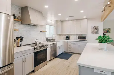 a kitchen with white cabinets and white counter tops at Dennison House in Three Rivers