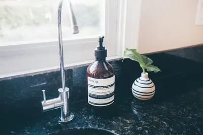a bottle of alcohol sitting on a counter next to a sink at Oasis East Sac Charming Home with Saltwater Pool and Casita in Sacramento