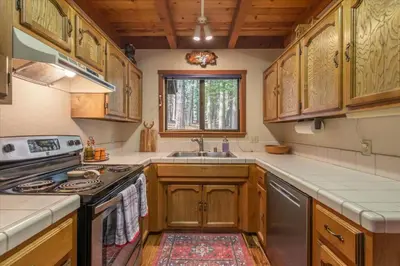 a kitchen with wooden cabinets and a stove top oven at 3BR Tahoe Donner Cabin with HOA Perks like Pools Hot-Tub Minutes to Trails Lake Golf in Truckee