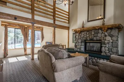 a living room with a stone fireplace and chairs at Summit Forester #47 BLDG.2 Bedrm / 2 bath Ski in Ski Out! Steps to Chair 15 at Little Eagle Lodge! in Mammoth Lakes