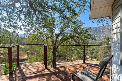 a deck with a chair and a view of the mountains at Views, Hot Tub, Outdoor Shower, 15m from Sequoia in Three Rivers