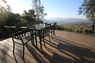 a table and chairs sitting on a deck with a view at High End A-Frame - Hot Tub - Awesome Views - Yosemite - Electric Vehicle Friendly - Sleeps 10 in Oakhurst