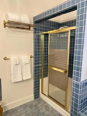 a blue tiled bathroom with a shower and towels at The Shopkeeper's Cottage ~ CHIC! in Amador City