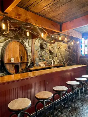 a bar with wooden stools and a stone wall at Vintage 1857~Stone & Beam Cellar in Amador City