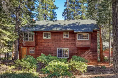 a red brick house in the woods with trees at Alpen Glow by Tahoe Getaways - Private Hot Tub, Close to Northstar in Carnelian Bay