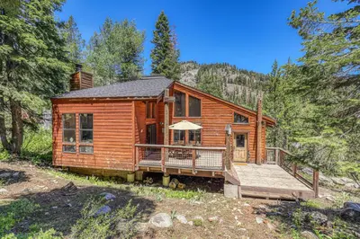 a log cabin in the woods with a deck at Alpine Escape by Tahoe Getaways - Shuttle to Ski Slopes & Fireplace in Alpine Meadows