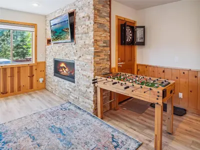 a game table in a room with a brick fireplace at Bear Peak Cabin by Tahoe Getaways - Tahoe Donner Rental with Private Hot Tub and Bonus Room in Truckee