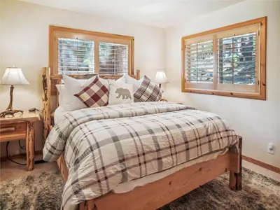 a bedroom with a bed and two windows at Bear Peak Cabin by Tahoe Getaways - Tahoe Donner Rental with Private Hot Tub and Bonus Room in Truckee