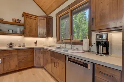 a kitchen with wooden cabinets and a sink and a window at Bluebird Lodge by Tahoe Getaways - 4 BR with Hot Tub, Pool Table & Lake Views in Carnelian Bay
